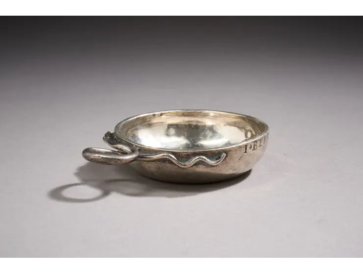 Une tasse à vin en argent à décor uni, la bordure gravée I Bertolle, l’anse en serpent stylisé.