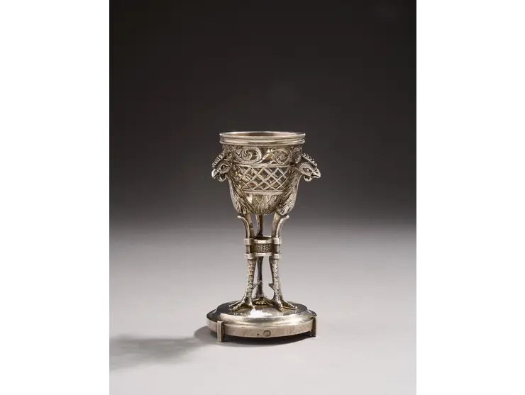 Coquetier en argent reposant sur une base circulaire à trois petits pieds unis.