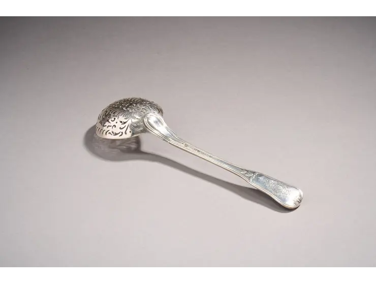 Cuillère à saupoudrer en argent du modèle double filets, la spatule à décors d’enroulements, feuilles d’acanthes et chute de fleurons.
